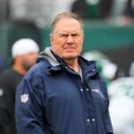 Bill Belichick stands on the field ahead of a game.
